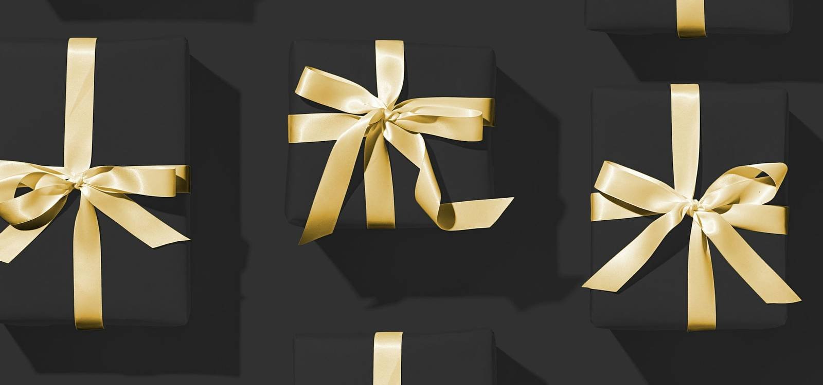 Black gift boxes tied with gold ribbon